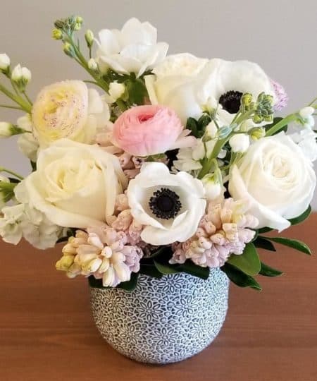 Sweet & petite, this blush & white arrangement features fragrant pink hyacinth, lush ranunculus and striking white anemones. Arranged in a decorative ceramic pot.