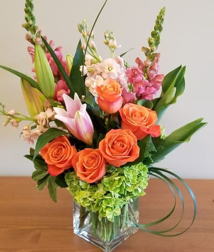 Arrangement of orange roses, green hydrangea and starburst lilies