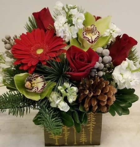 Red white and green flowers nestled into winter greens in a cute wood box.