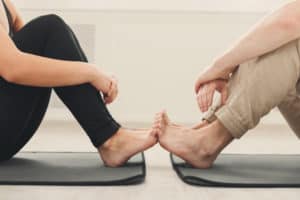Couple sitting on yoga mats feet to feet