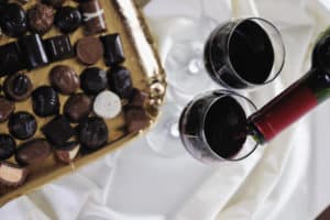 Assorted chocolate and pouring red wine into glasses