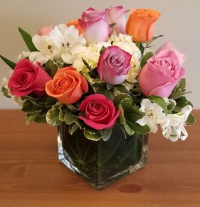 A dozen colorful roses nestled in hydrangea in a leaf lined cube. Available in pink, lavender, yellow, orange, peach and multi-colored.
